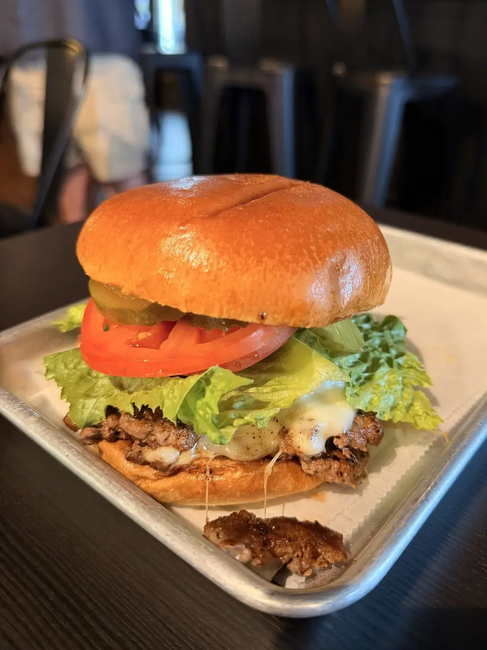 A smash burger with lettuce, tomato and pickles on a brioche bun